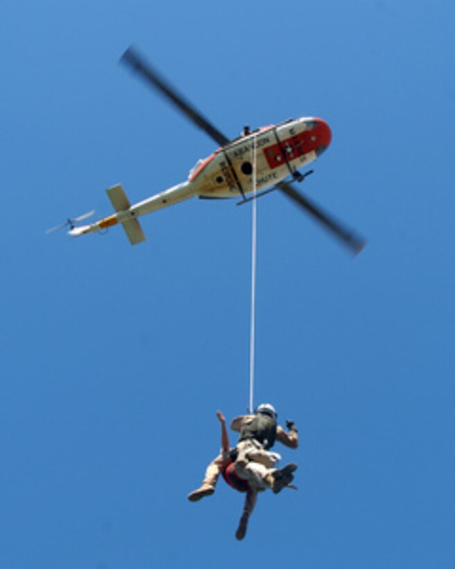 U.S. Navy Petty Officer 1st Class Jason Conley and U.S. Marine Capt. Dawn Steinberg hang from a UH-1N Huey search and rescue helicopter during a training exercise over Lake Martinez, Ariz., on June 16, 2006. Conley and Steinberg are with Headquarters and Headquarters Squadron, Marine Corps Air Station Yuma, Ariz. 