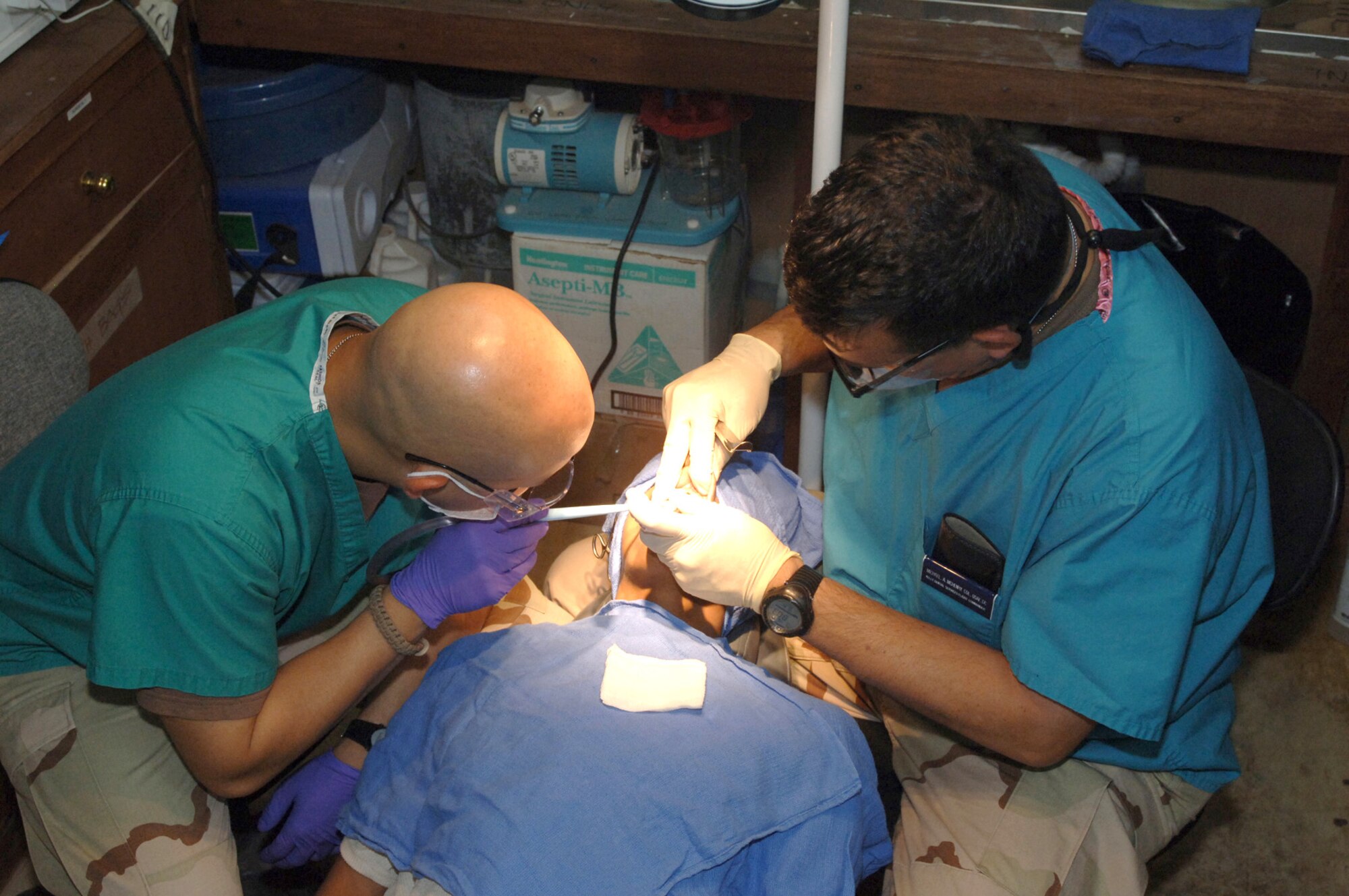 Col. (Dr.) Michael McHenry (right) extracts a tooth from an Iraqi patient at a medical clinic for Iraqi national police at the Victory Base Complex outside Baghdad, Iraq, on Wednesday, June 14. The colonel and his technician, Staff Sgt. Jose Cano, are deployed from Lackland Air Force Base, Texas. (U.S. Air Force photo/Staff Sgt. Bryan Bouchard)