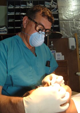 Col. (Dr.) Michael McHenry extracts a tooth from an Iraqi patient at a medical clinic for Iraqi national police at the Victory Base Complex outside Baghdad, Iraq, on Wednesday, June 14. (U.S. Air Force photo/Staff Sgt. Bryan Bouchard) 