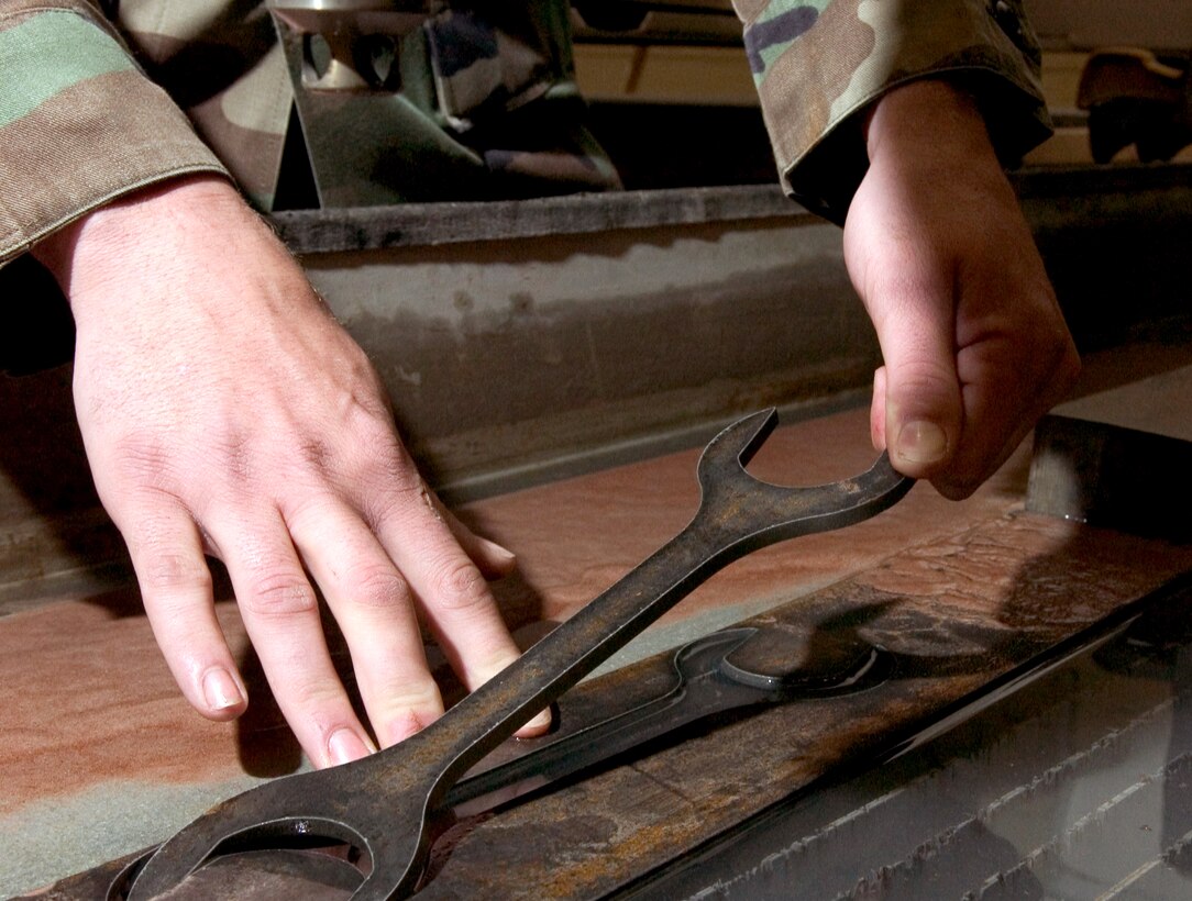 A technician from the 3rd Equipment Maintenance Squadron metals technology shop finishes producing a special tool using an abrasive water-jet cutter on Friday, June 16. (U.S. Air Force photo/Staff Sgt. Alan Port)