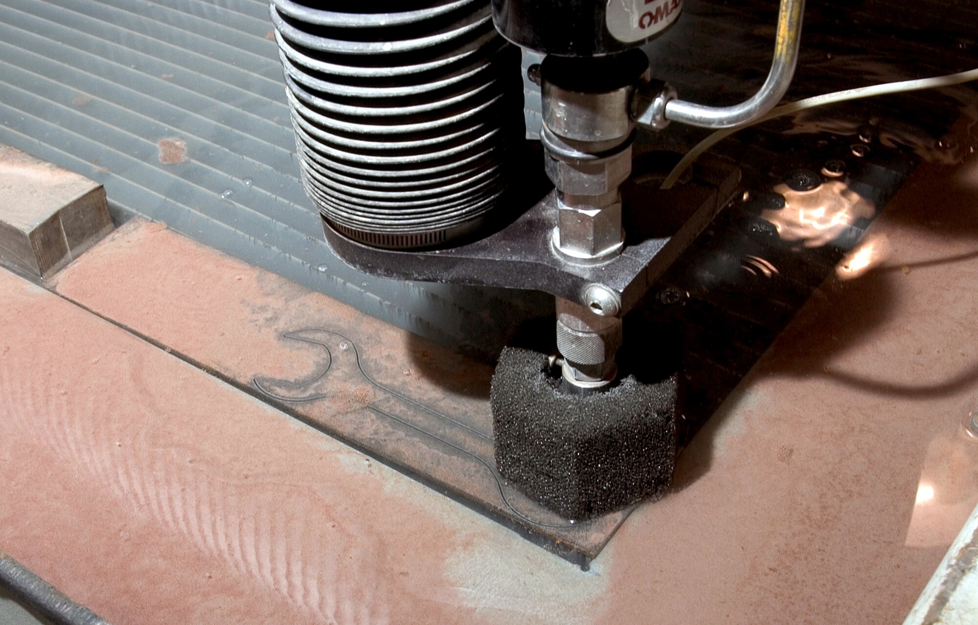 An abrasive water-jet cutter puts the final cuts on a special tool that is being created by Airmen assigned to the 3rd Equipment Maintenance Squadron metals technology shop at Elmendorf Air Force Base, Alaska, on Friday, June 16. (U.S. Air Force photo/Staff Sgt. Alan Port)