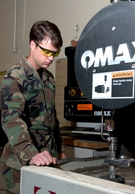 Tech. Sgt. Albern Warren checks on the progress of an abrasive water-jet cutter while cutting metal for an aircraft part on Friday, June 16. Sergeant Warren is assigned to the 3rd Equipment Maintenance Squadron metals technology shop at Elmendorf Air Force Base, Alaska. (U.S. Air Force photo/Staff Sgt. Alan Port)