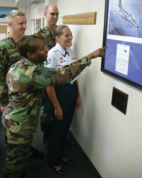 20th Communications Squadron volunteers along with an Airman Leadership School instructor admire the Voodoo legacy decor in an ALS classroom.  (U.S. Air Force Photo/Senior Airman John Gordinier)