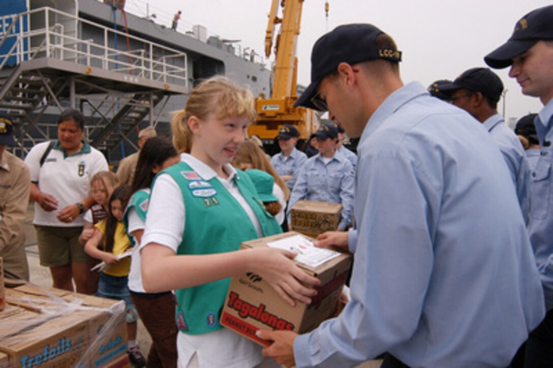 A Girl Scout from Girl Scout Junior Troop 71 delivers a case of Girl Scout cookies and a letter of appreciation to U.S. Navy Seaman Christian Shields in Yokosuka, Japan, on June 15, 2006. Over 24,000 cases of cookies were donated to Yokosuka to be divided among service members and were part of 194,762 boxes donated to military members around the world by the Girl Scouts. Shields is assigned to the amphibious command ship USS Blue Ridge (LCC 19). 