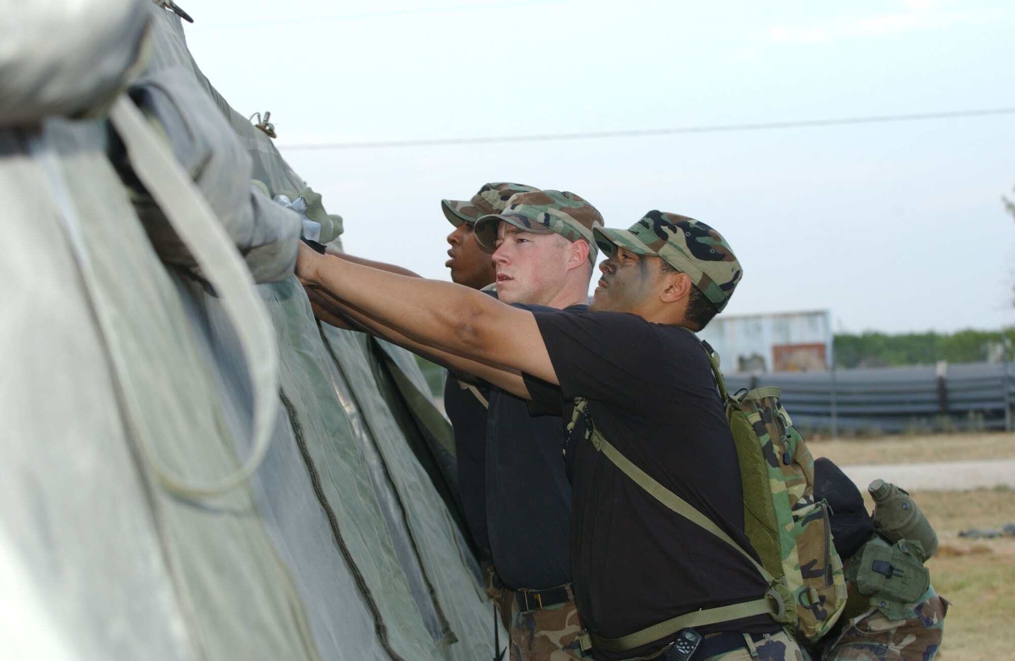Senior Airmen Sean Davis, Noah McCool, and Randall Thompson Jr. set up a tent to stay in overnight for the FTX here June 16.