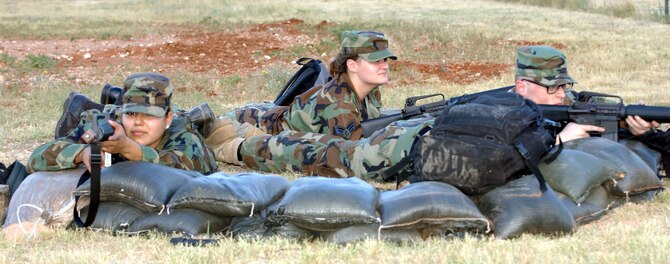 Airman Leadership School Senior Airmen Priscilla Cishero, Teri Barreno and David Kinnick assume a defensive fighting position behind sandbags during a field training exercise at the cantonment area June 16. The FTX is an opportunity for soon-to-be noncommissioned officers to practice combat leadership skills.                               