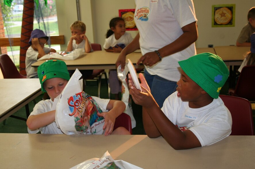 Two vacation Bible school children make paper plate artwork and decorate their green fisherman's hats during the arts and crafts projects hour.