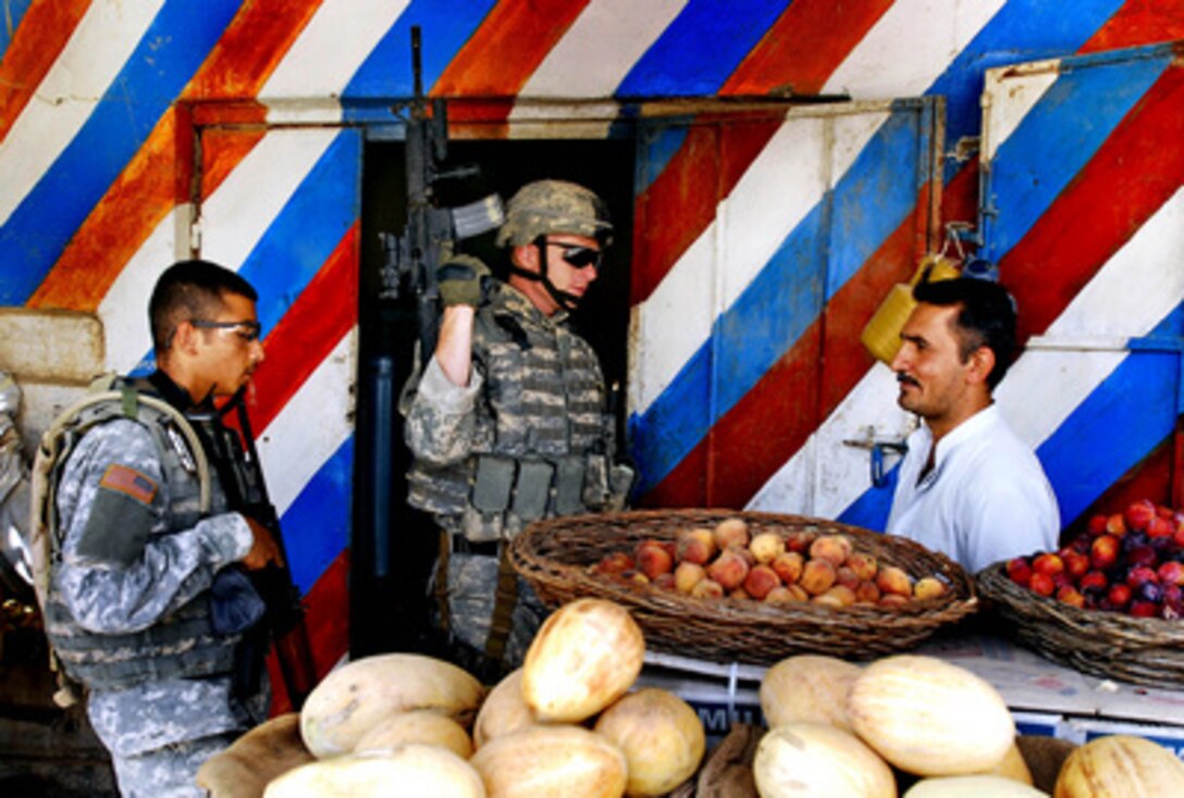 U.S. Army Staff Sgt. Paul Campbell (center) and his interpreter speak with a shop owner in Samarra, Iraq, during a routine patrol on June 18, 2006. Campbell is assigned to the 310th Tactical Psychological Operations Company attached to the 101st Airborne Division. 