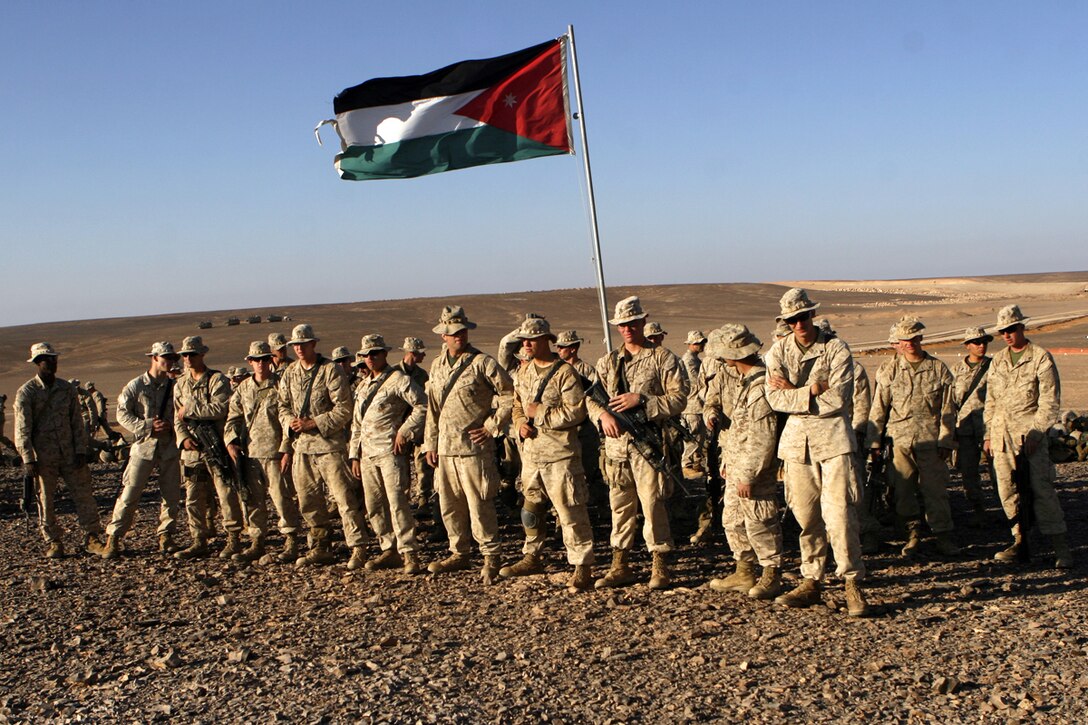 AL QATRANAH, Jordan, (Aug. 16, 2008) -- Marines with Fox Company, Battalion Landing Team 2/5, 15th Marine Expeditionary Unit, gather under the Jordanian flag during the bi-lateral training exercise "Infinite Moonlight" in the Jordanian desert.::r::::n::   Infinite Moonlight, a two-week exercise conducted by the U.S. military and the Jordanian Army, is designed to share tactical knowledge and build on the military ties between the United States and Jordan.::r::::n::   The Camp Pendleton, Calif. based 15th MEU is comprised of approximately 2,200 Marines and Sailors and is a forward deployed force of readiness capable of conducting numerous operations, such as Non-Combatant Evacuation Operations, Humanitarian Assistance Operations and a wide range of amphibious missions. ::r::::n::   The 15th MEU is currently conducting sustainment training in the desert of Jordan. (Official USMC photo by Cpl. Timothy T. Parish) (Released)::r::::n::