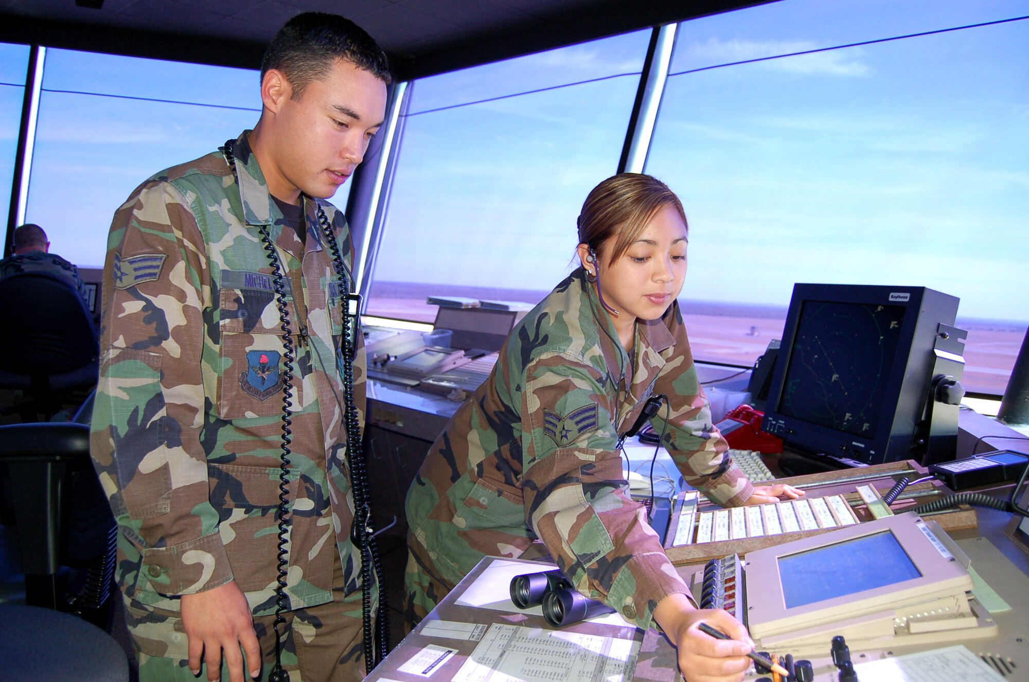 Senior Airman Jennifer Manibusan makes a note about the day's flights with guidance from Senior Airman Anthony Michels in the air traffic control tower at Laughlin Air Force Base, Texas, on June 26, 2006. Airman Manibusan, from Alameda, Calif., and Airman Michels, from Rosemont Minn., are air traffic controllers with the 47th Operations Support Squadron. (U.S. Air Force photo/Staff Sgt. Jeremy Larlee)