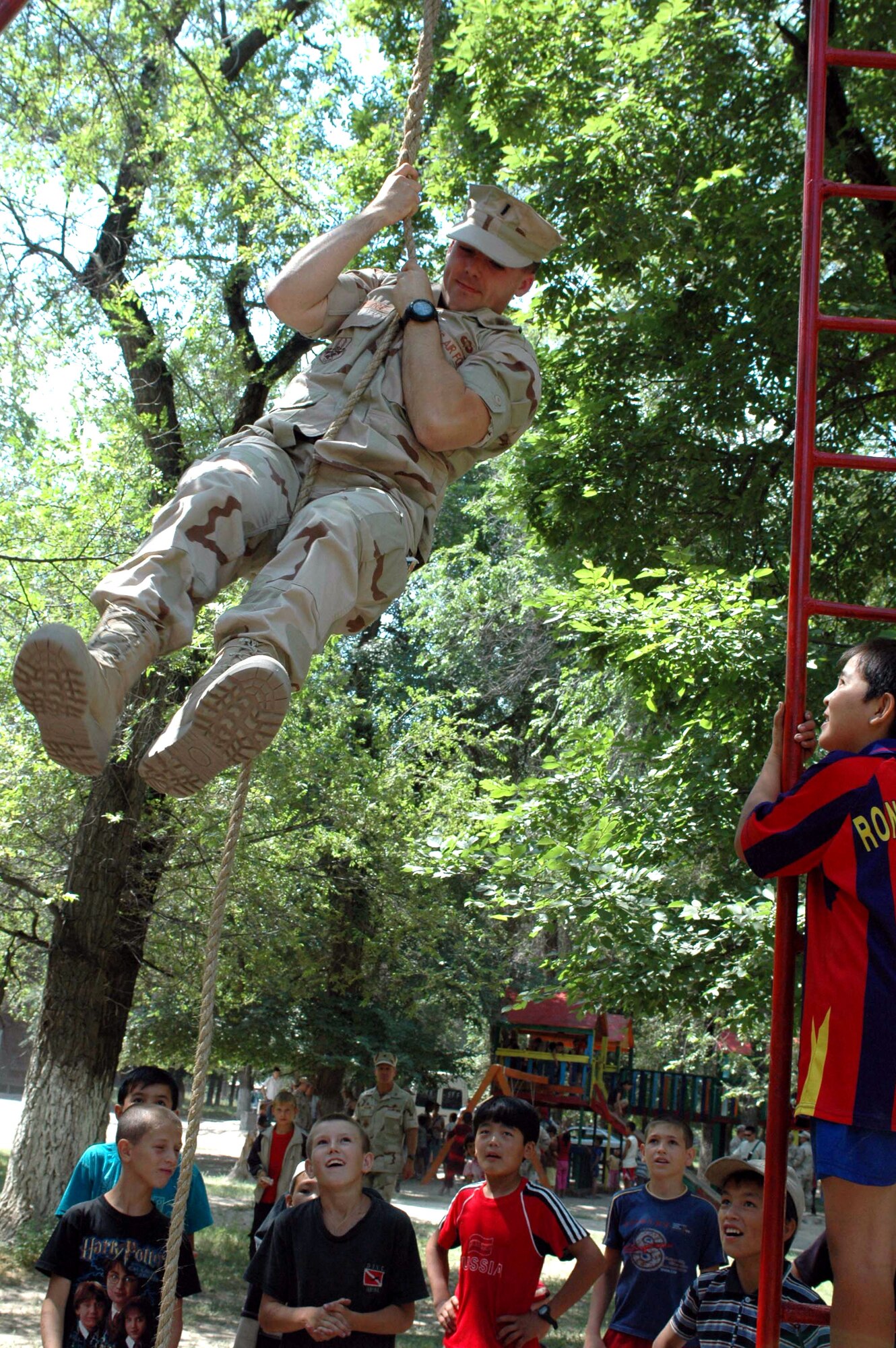 1st Lt. Tobey Hockridge, 376th Air Expeditionary Wing, Manas Air Base, Kyrgyzstan, climbs to the top of a rope, dazzling Oktobersky Village, Kyrgyzstan children.  Members from the 376th AEW were on hand to dedicate a new children's playground, built by members of the 376th Expeditionary Security Forces and Civil Engineer squadrons.  Lieutenant Hockridge is deployed from the 43d Communications Squadron, Pope Air Force Base, N.C.  (U.S. Air Force photo/Staff Sgt. Candy Knight)