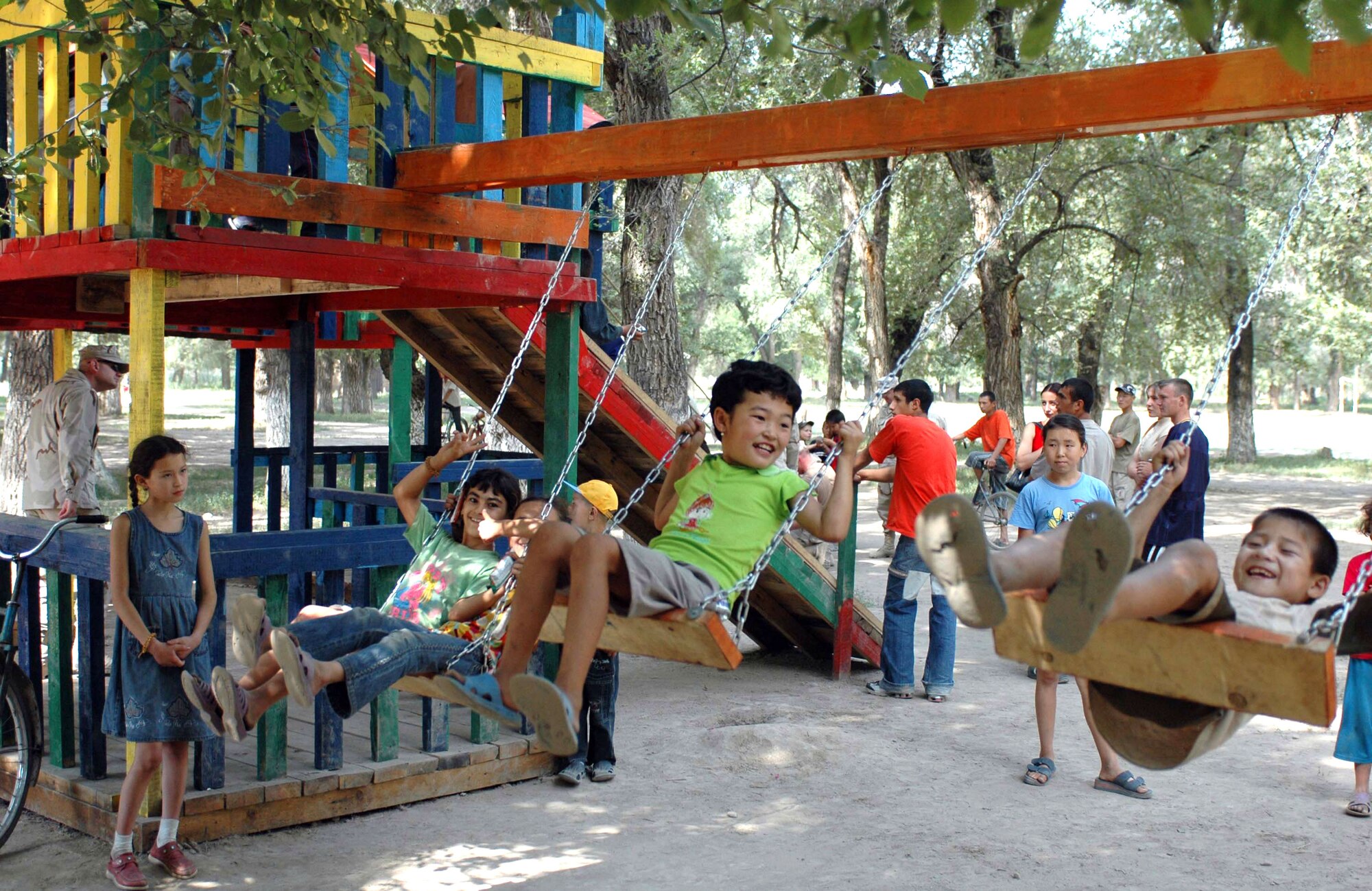 Oktobersky Village, Kyrgyzstan children enjoy swinging on their new playground's swing set. Members from the 376th Air Expeditionary Wing at Manas Air Base, Kyrgyzstan, were on hand to dedicate the new playground, built by members of the 376th Expeditionary Security Forces and Civil Engineer squadrons.  (U.S. Air Force photo/Staff Sgt. Candy Knight) 