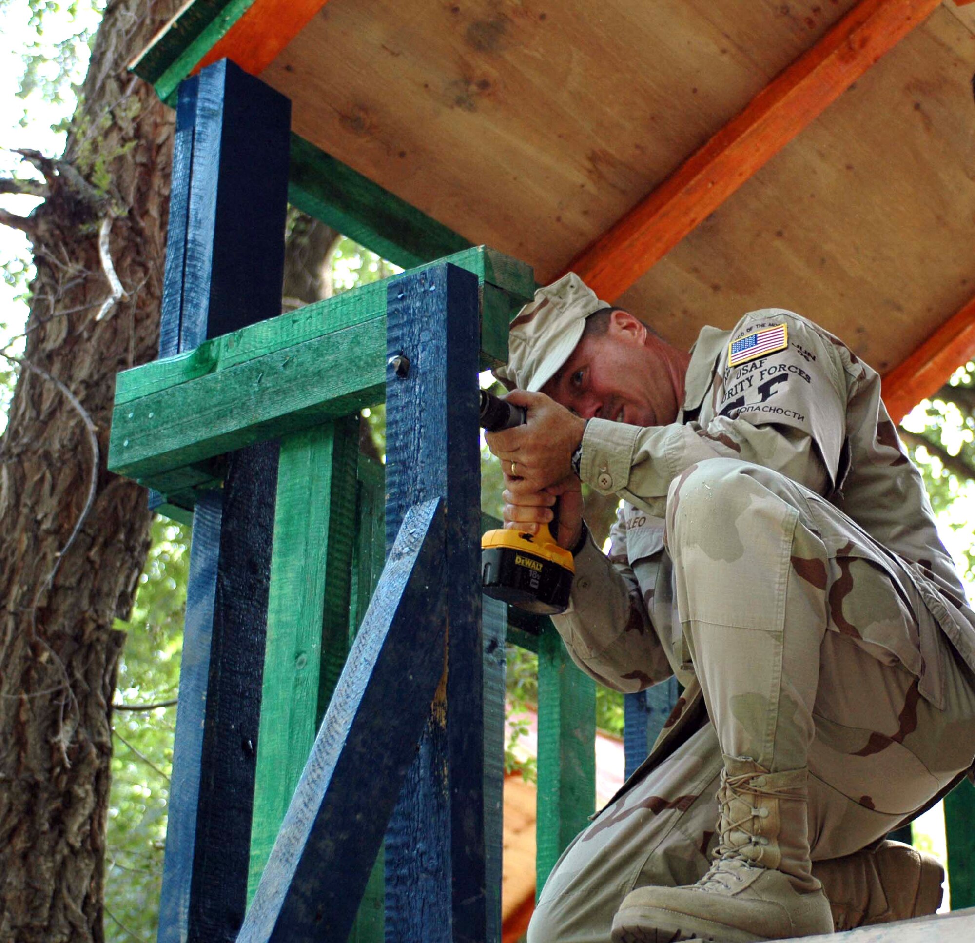 Tech Sgt. Edward Sileo, 376th Expeditionary Security Forces Squadron, drills a hole to attach a rope ladder to a playhouse at the new Oktobersky Village, Kyrgyzstan, School #1 children's playground. Members from the 376th Air Expeditionary Wing at Manas Air Base, Kyrgyzstan, were on hand to dedicate a new children's playground, built by members of the 376th ESF and Civil Engineer squadrons. Sergeant Sileo is deployed from the 482nd Security Forces Squadron, Homestead Air Reserve Base, Fla.  (U.S. Air Force photo/Staff Sgt. Candy Knight) 

