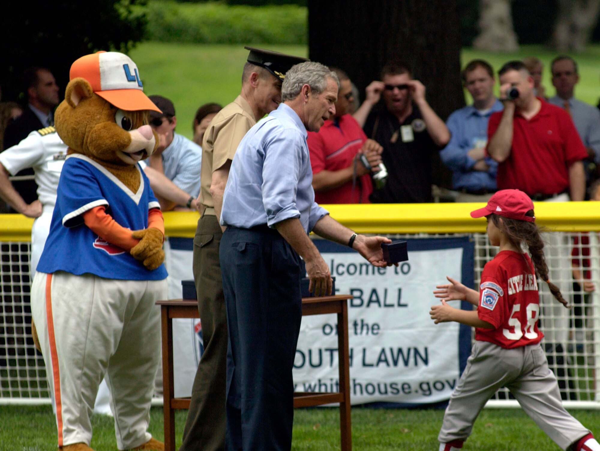 President George W. Bush gives a ceremonial ball to Mia Martin of the McGuire AFB, N.J., Little League Yankees at the conclusion of the "Tee Ball on the South Lawn" game on Friday, June 23. The Little League mascot, Dugout, and Gen. Peter Pace, chairman of the Joint Chiefs of Staff add their congratulations.  The game marked the official start of the Little League season.  The Yankees played against the Dolcom Little League Indians of Naval Submarine Base New London, Groton, Conn. (U.S. Air Force photo/Tech. Sgt. Cohen A. Young)