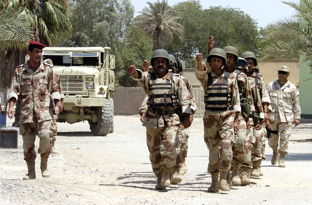 Iraqi soldiers march through Camp Rustamiyah, Iraq, as Army Sgt. 1st Class Carlos Martinez watches on Thursday, June 22. The soldiers are with the base defense battalion preparing to take over security for the camp, which houses NATO forces and the Iraqi Military Academy. Sergeant Martinez is with the NATO certification team that is validating the battalion before it takes over. (U.S. Air Force photo/Senior Airman Brian Ferguson) 