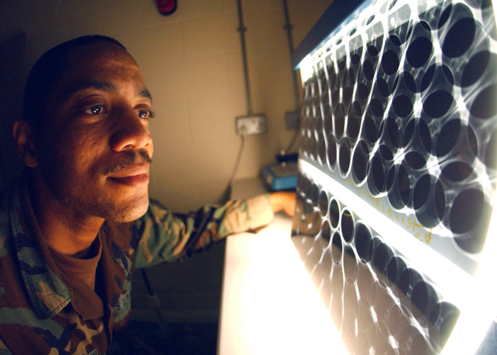 Staff Sgt. Corey Fletcher looks at X-rays from an MH-53 Pave Low engine air particle separator at Royal Air Force Base Mildenhall, England, on Tuesday, June 20. Sergeant Fletcher checks for structural flaws, cracks, defects and foreign object damage in aircraft parts by using X-rays and flourescent green penetrant. He is a non-destructive inspection specialist with the 100th Maintenance Squadron. (U.S. Air Force photo/Staff Sgt. Tyrona Pearsall)
