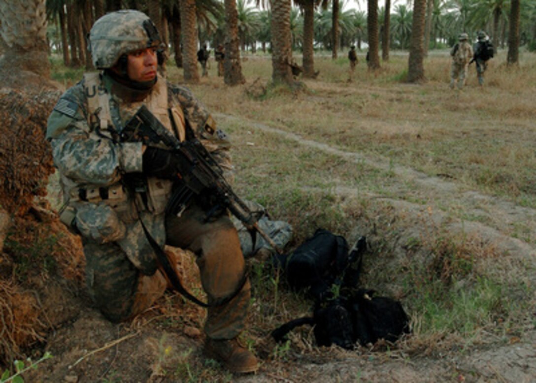 U.S. Army Staff Sgt. Danny Jimenez kneels on one knee as he provides perimeter security for his fellow soldiers during an air- assault raid on a suspected insurgent sanctuary in Mushada, Iraq, on June 23, 2006. Jimenez is from the 1st Battalion, 66th Armor Regiment, 1st Brigade Combat Team, 4th Infantry Division. 
