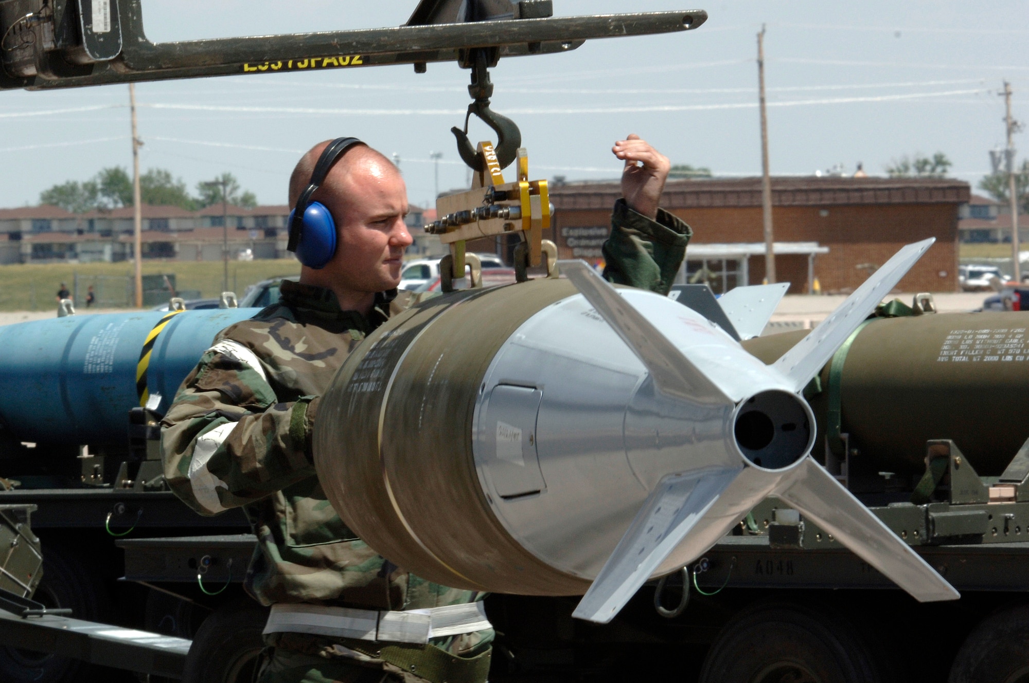 Senior Airman Ryan McGlocklin directs a bomb loader into position underneath a training bomb at Ellsworth Air Force Base, S.D., on Monday, June 26. The base is conducting Exercise Badlands Express 06-04 to prepare for an operational readiness inspection in July. Airman McGlocklin is assigned to the 28th Aircraft Maintenance Squadron. (U.S. Air Force photo/Senior Airman Michael B. Keller) 
