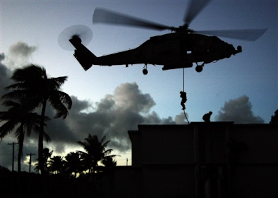 U.S. Navy sailors from special warfare units fast rope from an HH-60H helicopter assigned to the "Golden Falcons" of Helicopter Anti-Submarine Squadron 2 on a rooftop on the island of Guam, June 20, 2006, as part of exercise Valiant Shield 2006.