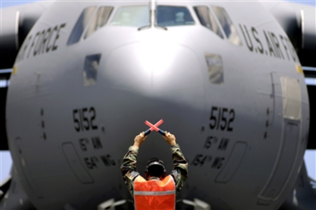 U.S. Air Force Tech. Sgt. Ronald Timbreza marshals the C-17 Globemaster III, "Spirit of 'Go for Broke'," to its parking spot at Hickam Air Force Base, Hawaii, June 14, 2006. The aircraft is named in honor of the highly decorated World War II veterans of the 442nd Regimental Combat Team, comprised of 3,800 Japanese Americans.