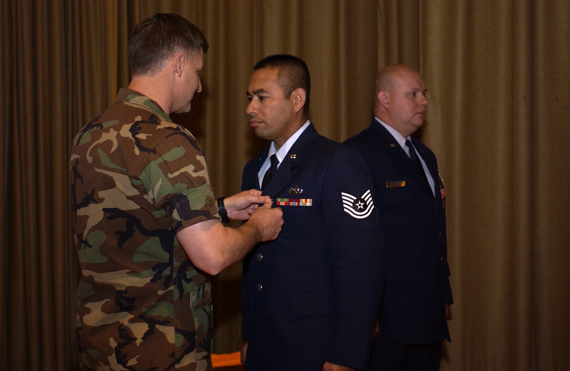 Tech. Sgt. Tyrone Sevening receives the Bronze Star Medal from Col. Michael Bartley, 99th Air Base Wing commander, Monday during commander's call in the base theater at Nellis Air Force Base, Nev. Tech. Sgt. Andrew Morin (right) also received the Bronze Star. Both NCOs, assigned to the 99th Logistics Readiness Squadron, were convoy commanders in Iraq. (U.S. Air Force photo/Staff Sgt. Colette Bennett)