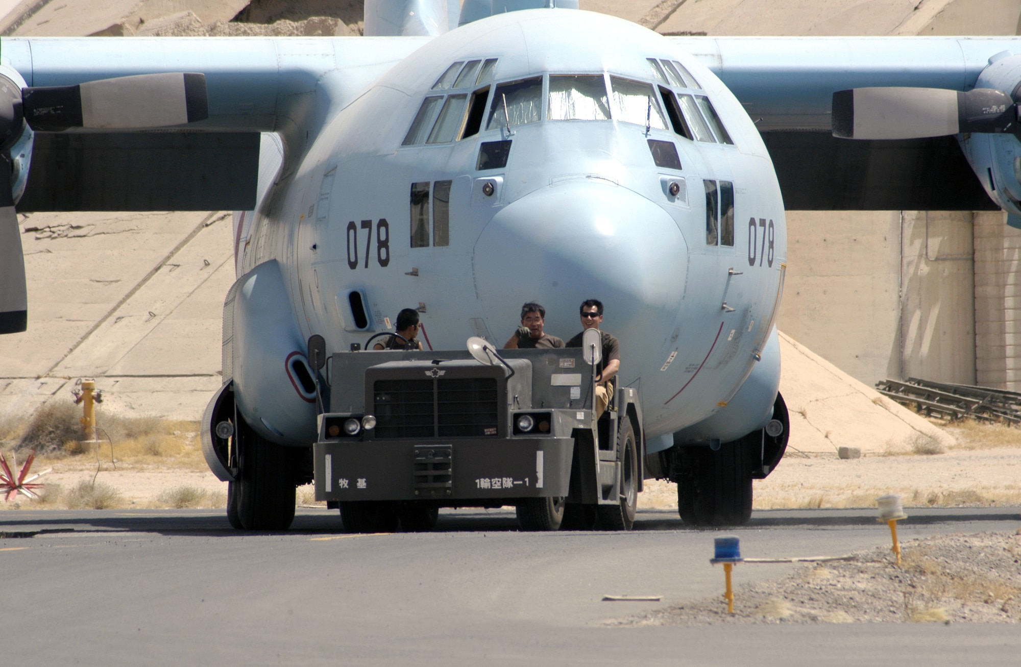 Maintainers from the Japan Air Self-Defense Force's Iraq Reconstruction Support Airlift Wing tow one of their C-130s from the flightline at a forward operating base in Southwest Asia. (U.S. Air Force photo/Staff Sgt. Ryan Hansen) 

