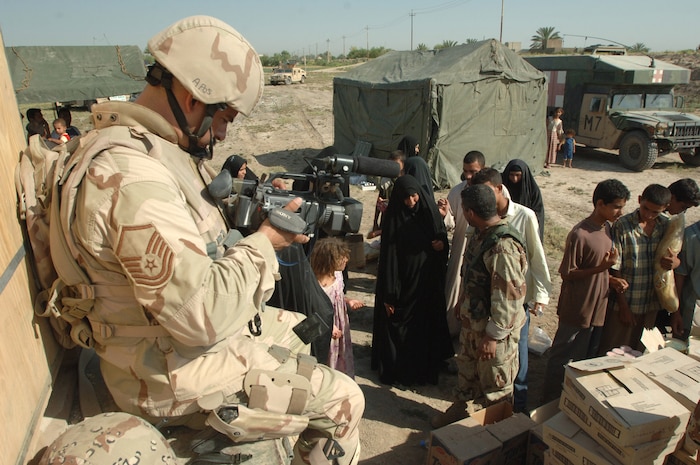 Master Sgt. Christopher Nolan videotapes Iraqi soldiers handing out food, toys and blankets to Iraqi citizens during an Army exercise conducted in Baghdad, Iraq, on Saturday, June 24. Sergeant Nolan is a combat videographer with the 1st Combat Camera Squadron at Charleston Air Force Base, S.C. (U.S. Army photo by Staff Sgt. Kevin L. Moses Sr.)
