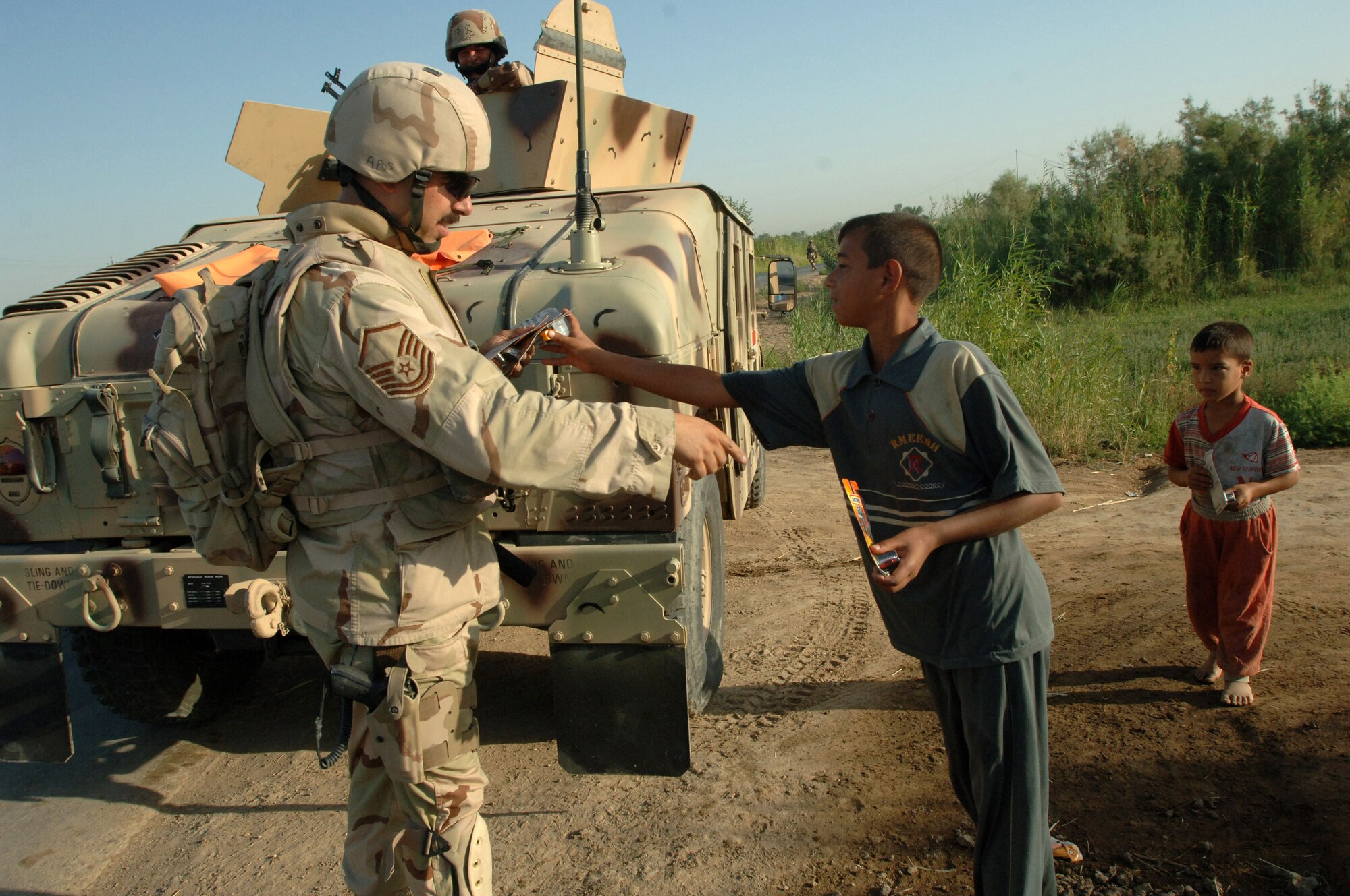 Master Sgt. Christopher Nolan gives out toys to children before the start of an Army exercise conducted in Baghdad, Iraq, on Saturday, June 24. Sergeant Nolan is a combat videographer with the 1st Combat Camera Squadron at Charleston Air Force Base, S.C. (U.S. Army photo/Staff Sgt. Kevin L. Moses Sr.) 
