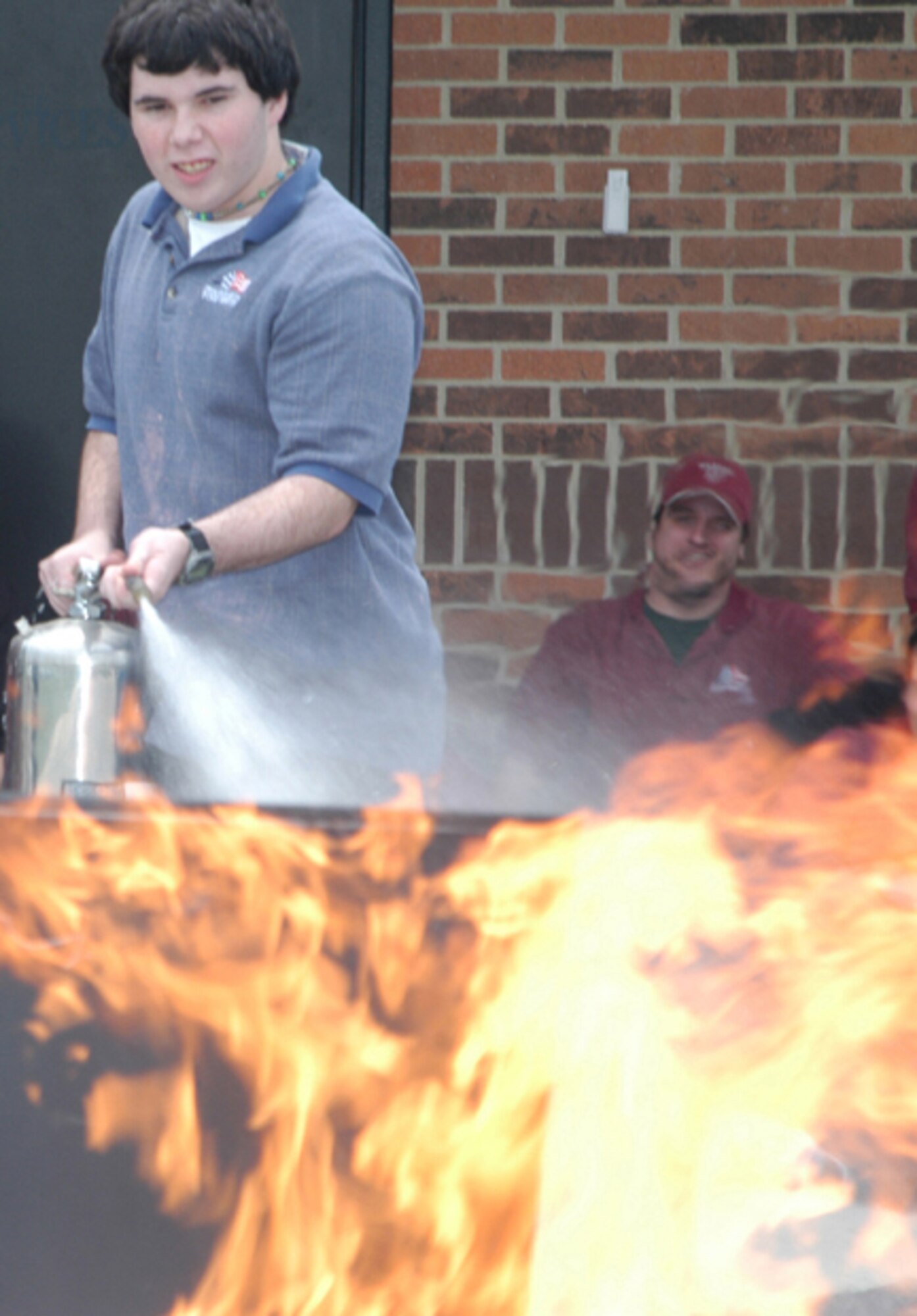 GRISSOM AIR RESERVE BASE, Ind.--- Matt Conlon, a civilian employee with the 434th Services Flight at Grissom Air Reserve Base, douses a fire during a safety training course as Josh Hinshaw watches.  The training course was supervised by the Grissom Fire Department's Fire Prevention Office and provided the employees with hands-on training in the use of a fire extinguisher. (U.S. Air Force photo/SrA Roberto Model)