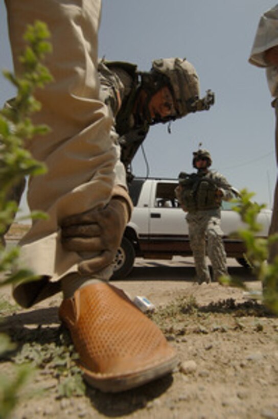 Army Staff Sgt. Gilbert Romero searches an Iraqi man while another soldier provides security at a traffic control zone on Route Tampa in Mosul, Iraq, on June 26, 2006. The soldiers are from 1st Battalion, 17th Infantry Regiment, 172nd Stryker Brigade Combat Team, based out of Fort Wainwright, Alaska. 