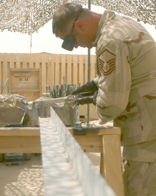 Master Sgt. Frank Swygert cuts a piece of angle iron using an acetylene torch at Kandahar Airfield, Afghanistan.  The angle iron will be used as a brace for radio antennas at a new air traffic control facility.  Sergeant Swygert overcame a shortage of parts to construct mounts for the antennas.  He is deployed to Kandahar from Dover Air Force Base, Del.  (US Air Force photo/Maj. David Kurle)