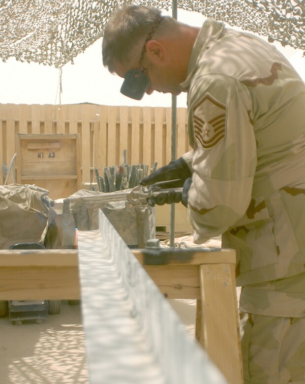 Master Sgt. Frank Swygert cuts a piece of angle iron using an acetylene torch at Kandahar Airfield, Afghanistan.  The angle iron will be used as a brace for radio antennas at a new air traffic control facility.  Sergeant Swygert overcame a shortage of parts to construct mounts for the antennas.  He is deployed to Kandahar from Dover Air Force Base, Del.  (US Air Force photo/Maj. David Kurle)