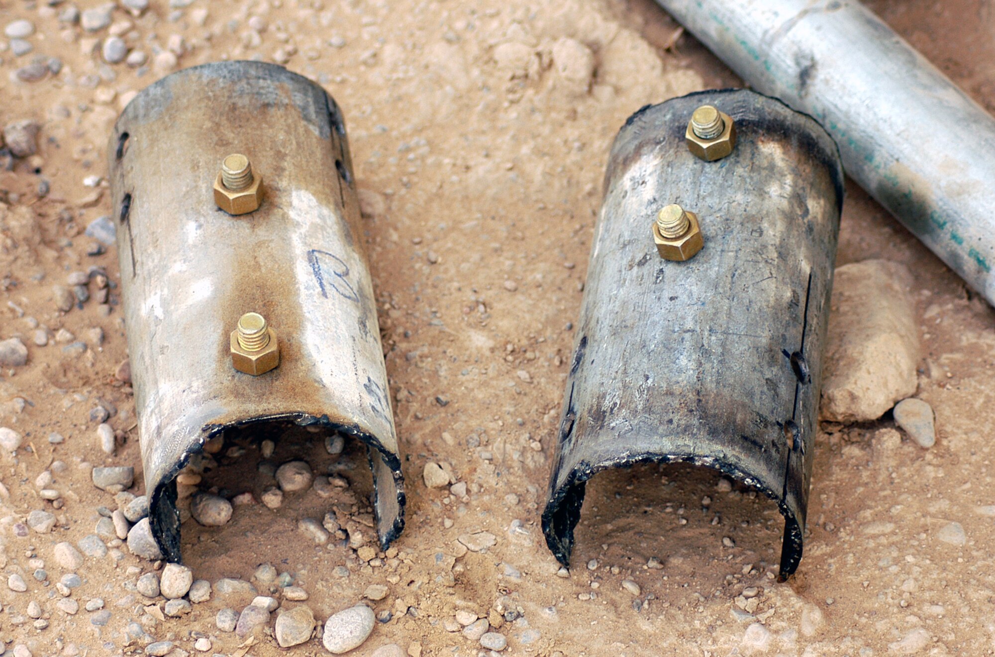 Two of the pieces of mounting hardware fabricated by Master Sgt. Frank Swygert, from the 451st Civil Engineer Flight,  lie on the ground, ready to attach radio antennas to mounting poles at a new air traffic control facility at Kandahar Airfield, Afghanistan.  Sergeant Swygert made the parts from 3 1/2-inch pipe found by the side of the road.  (US Air Force photo/Maj. David Kurle)