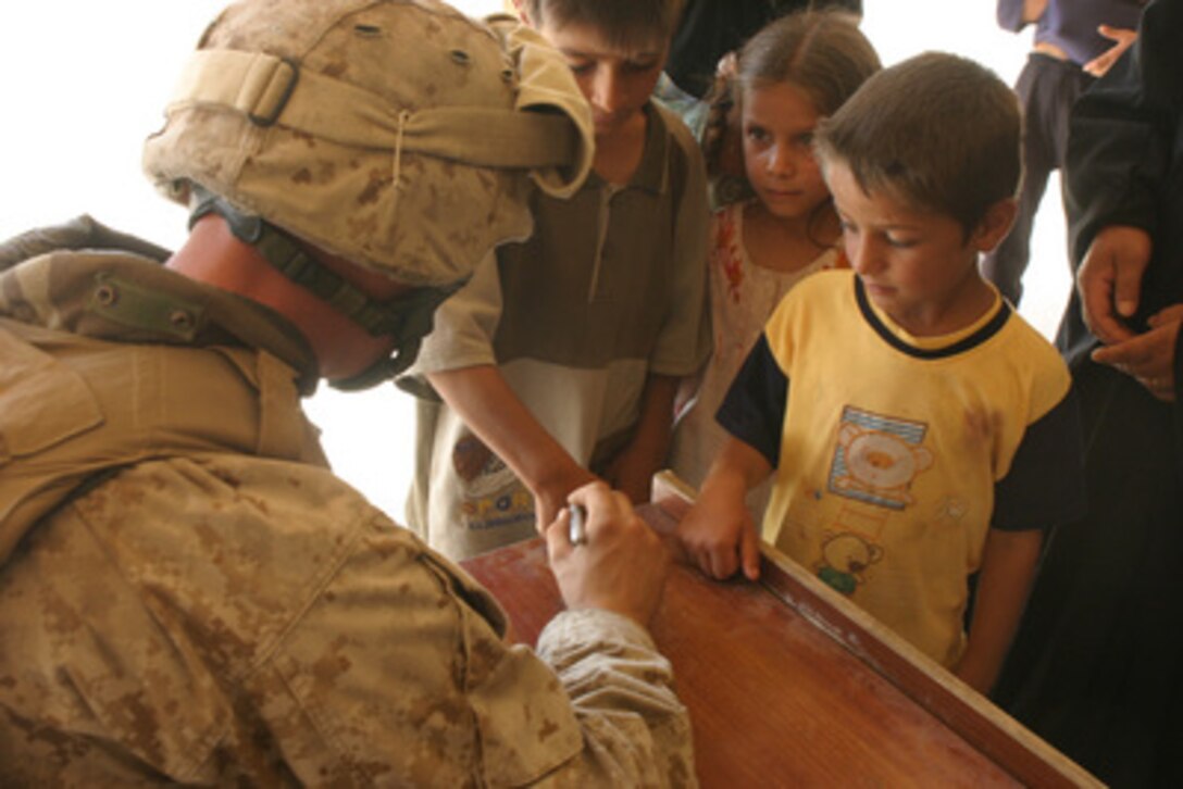 A U.S. Navy corpsman marks the hand of an Iraqi patient who needs to be screened for treatment during a medical operation at an abandoned schoolhouse in Kharma, Iraq, on June 22, 2006. The corpsman is assigned to 1st Battalion, 1st Marine Regiment, Regimental Combat Team 5. 