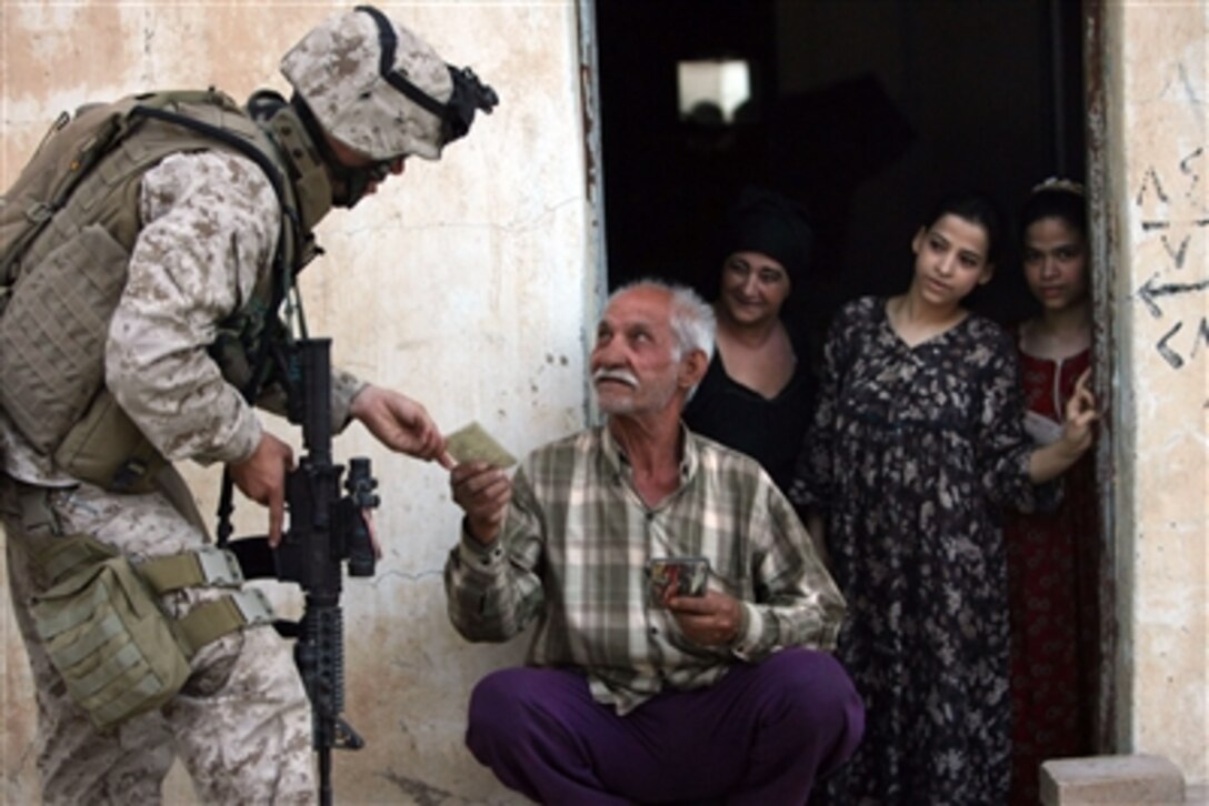 U.S. Navy Seaman Cameron R. Cleveland makes it a point to stop and visit with the local Fallujans while patrolling in Fallujah, Iraq, May 30, 2006. Here, a local man shares a family photo with the sailor. Cleveland is a corpsman with A Company, 1st Battalion, 25th Marine Regiment, Regimental Combat Team 5.