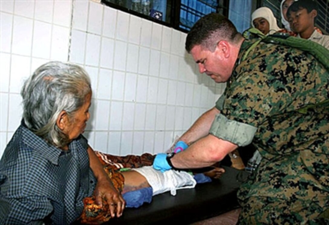 U.S. Navy Lt. Cmdr. Carlos Godinez applies a makeshift splint to the broken leg of Sudi Utomo in Bantul, Indonesia, May 31 after a 6.2 magnitude earthquake struck the island of Java. Utomo received the injury when a wooden beam fell on her during the earthquake. Godinez is a III Marine Expeditionary Force surgeon.