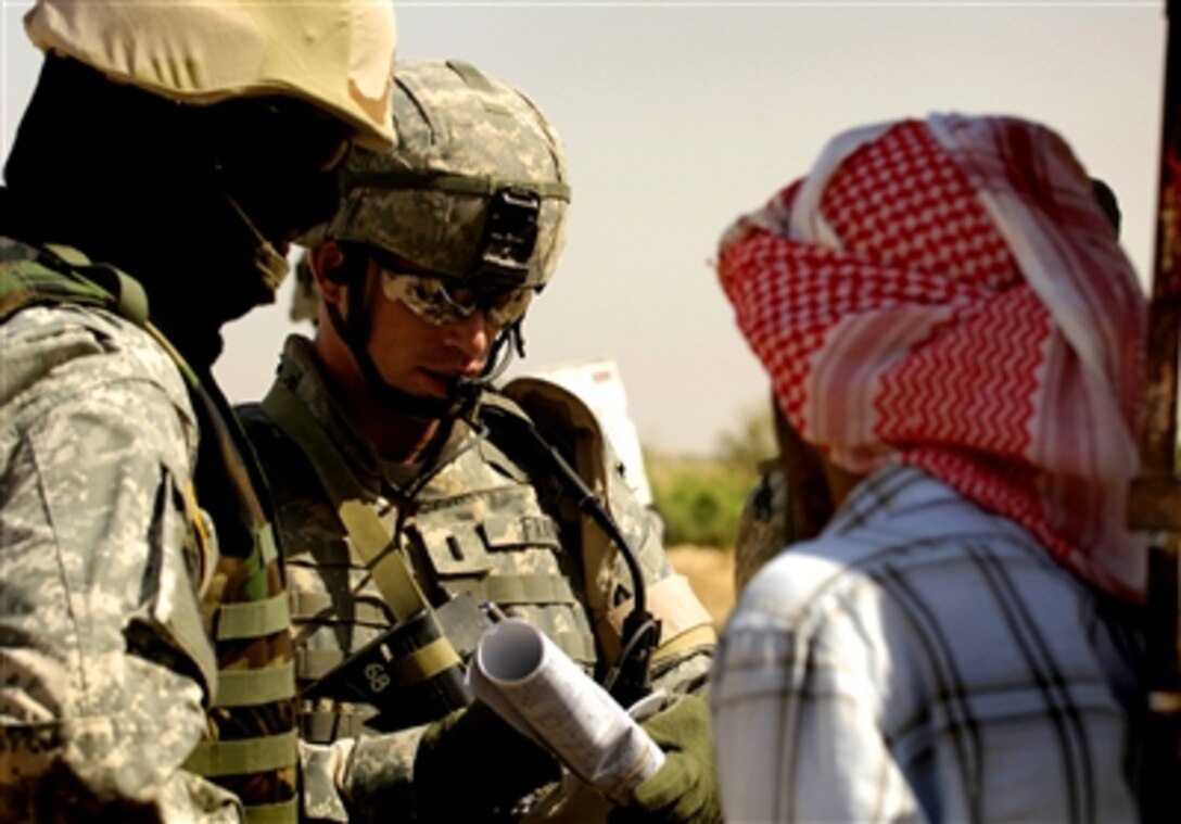 U. S. Army 1st Lt. Michael Frank (center), of Charlie Company, 1st Battalion, 327th Infantry Regiment, questions a gasoline vendor along the main road next to Rashad, Iraq, during a patrol, May 23, 2006. Frank and other soldiers visited with the Rashad Iraq Police and assessed the market area.