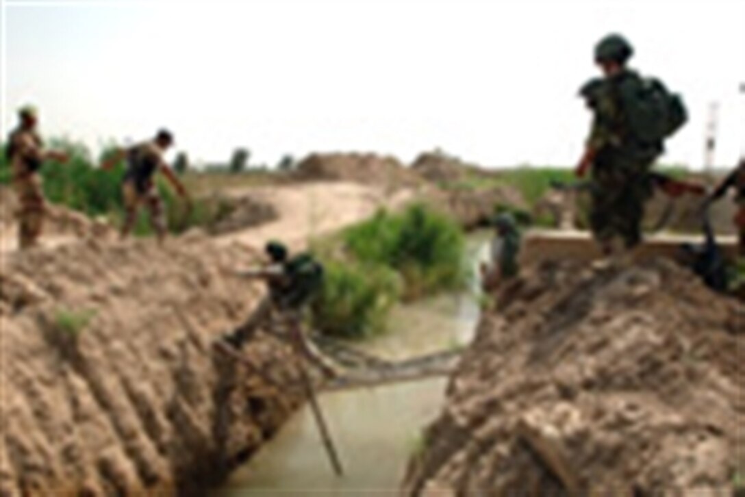 Iraqi army soldiers from 2nd Battalion, 4th Brigade, 6th Infantry Regiment use an improvised bridge to cross a canal during an air assault mission in Muhmudiyah, Iraq, May 15, 2006. 