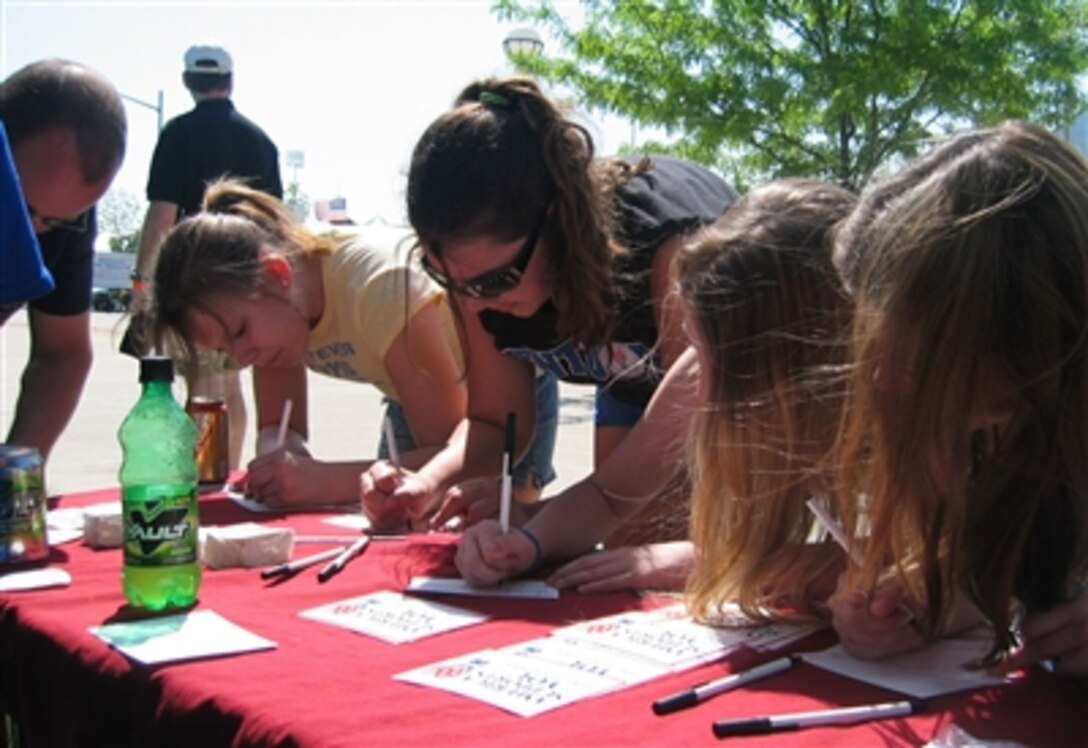Visitors to the America Supports You booth at the "Thunder Over Louisville" festival in Louisville, Ky., write messages of support on postcards for servicemembers deployed to Iraq and Afghanistan, April 22, 2006. Louisville became an America Supports You partner April 21, 2006, as part of the kick-off for this year's Kentucky Derby Festival. 