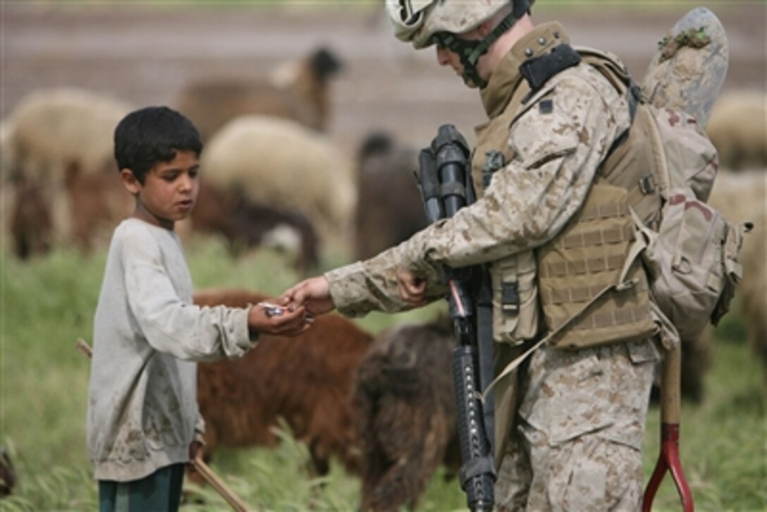 U.S. Marine Pfc. Ryan C. Freeman with 1st Battalion, 1st Marine Regiment's engineer platoon, hands some candy to a young Iraqi boy while conducting weapons searches in the area surrounding Gharmah, Iraq, April 6, 2006. The Marines and Iraqi soldiers conducted searches during Operation Hastings. 