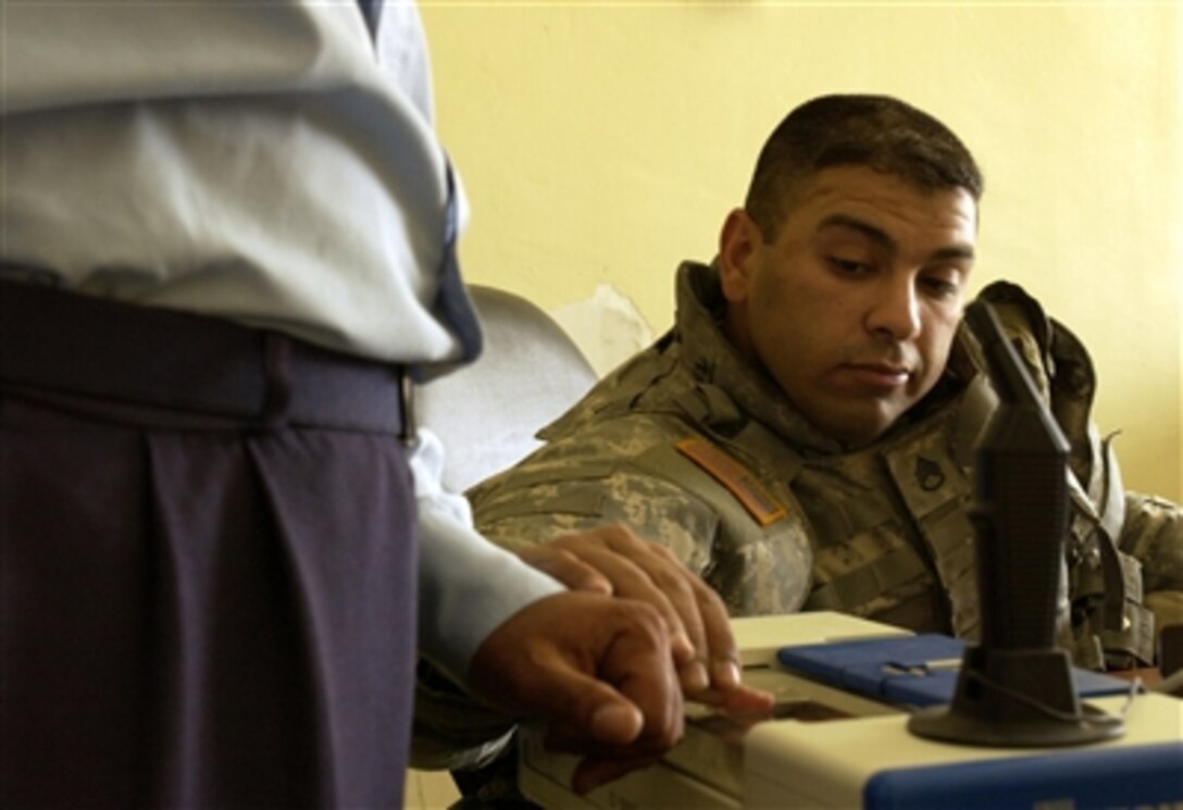 U.S. Army Staff Sgt. Frank Narro, of the 463rd Military Police Company, fingerprints an Iraqi policeman prior to entering him into a database in the police station in Abu Ghraib, Iraq, April 4, 2006. 