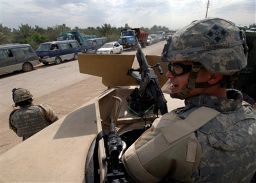 U.S. Army Cpl. Bartholomew Anderson mans a turret atop a Humvee as traffic is reduced to one lane into the town of Tarmiyah, Iraq, March 28, 2006, during increased counterinsurgency operations in the area. 