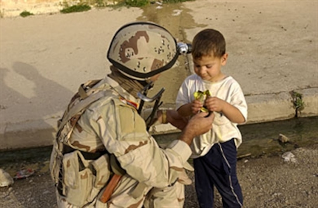 An Iraqi army soldier gives a young boy a snack during a cordon and search of homes with Iraqi police in Mosul, Iraq, May 4, 2006.