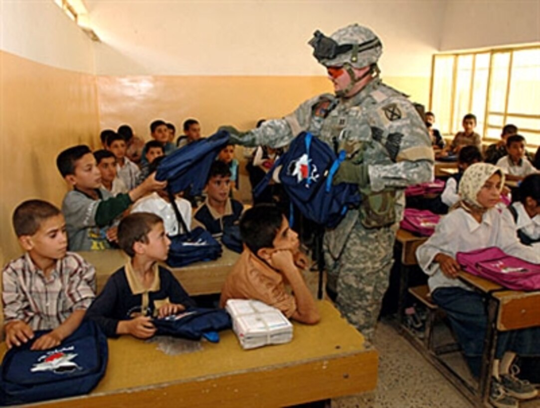 U.S. Army Capt. Gregory Stone hands out backpacks full of supplies to students in a classroom in Al Meshreca, Iraq, May 2, 2006. Stone is from 1st Battalion, 71st Cavalry Regiment.