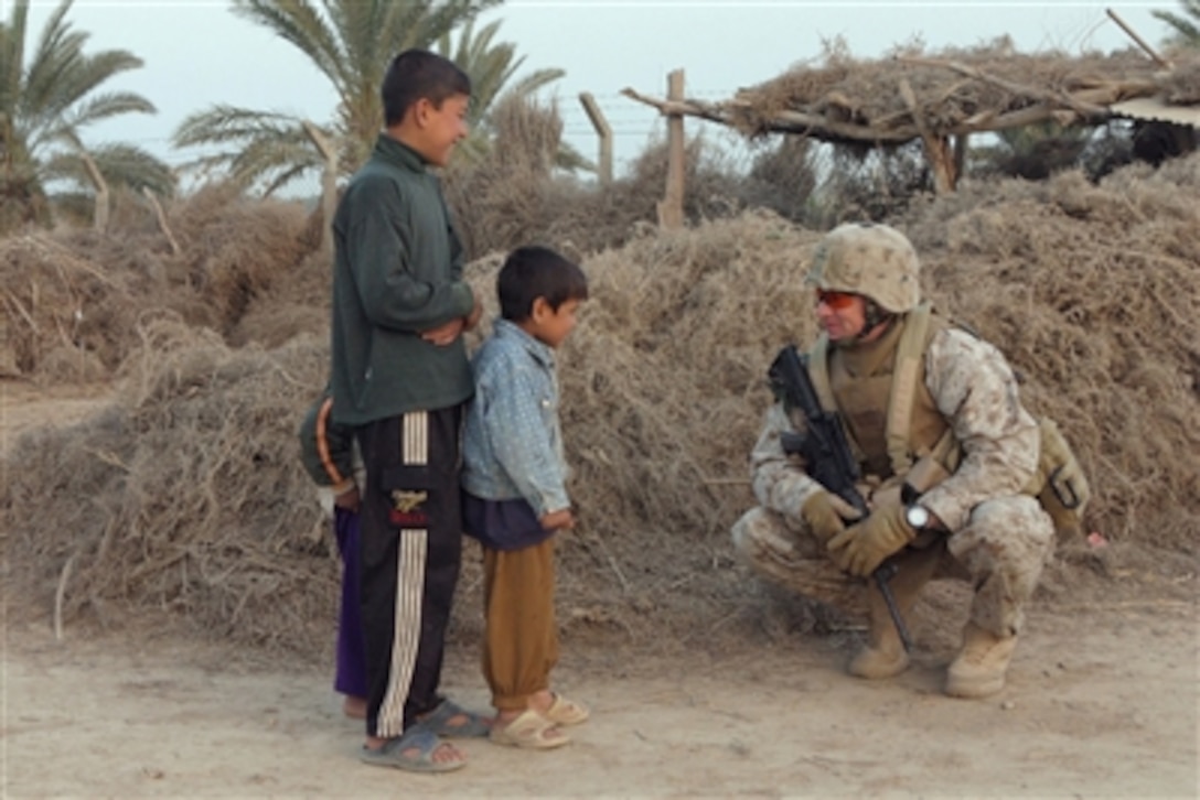 U.S. Marine Corps Staff Sgt. Foster, with Fox Company, 2nd Battalion, 6th Marine Regiment, Regimental Combat Team 5, talks with children during a patrol along the Euphrates River in Fallujah, Iraq, March 15, 2006.
