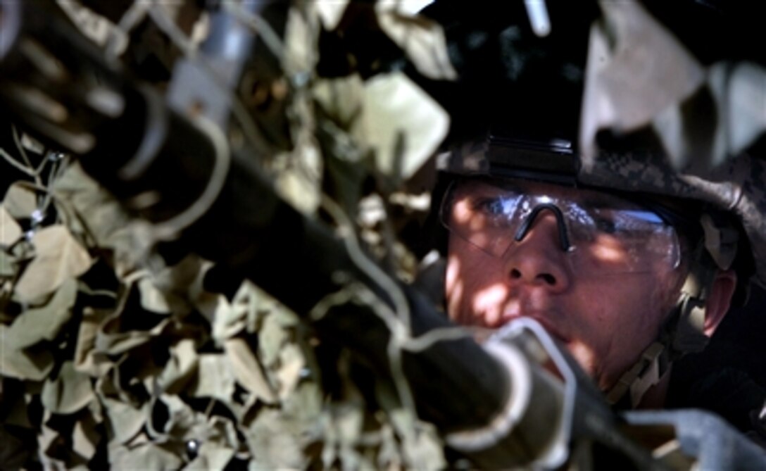 U.S. Army Spc. Jason Raymond stands guard in a tower draped with camouflage netting at Forward Operations Base Taji in Iraq, March 19, 2006.