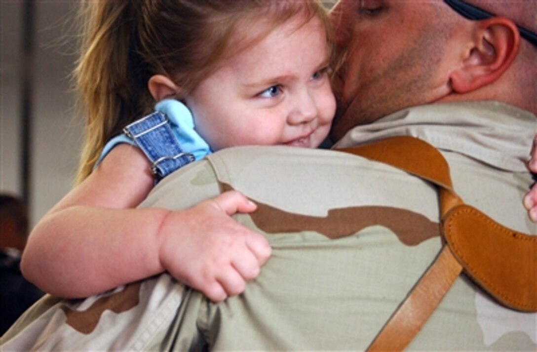 U.S. Navy Petty Officer 1st Class John L. Tatro with Navy Cargo Handling Battalion 1 kisses his daughter after returning to Naval Station Norfolk, Va., from Kuwait, March 10, 2006. Navy Expeditionary Logistics Support Group, Port Group Charlie returned home after completing their port vessel operations mission in Kuwait.