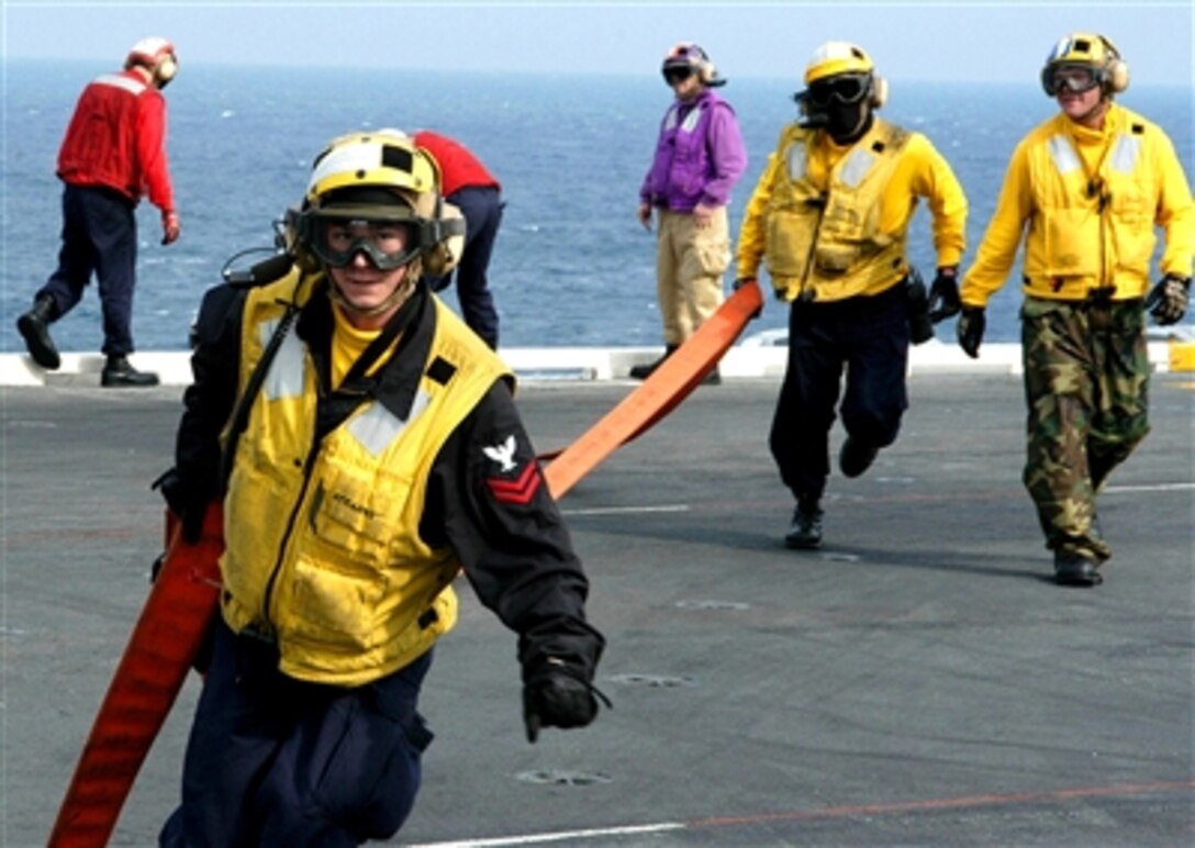 U.S. Navy sailors from Air Department run a fire hose to a hose team to fight a simulated aircraft fire on the flight deck aboard the Nimitz-class aircraft carrier USS Dwight D. Eisenhower in the Atlantic Ocean, March 3, 2006. The Eisenhower and embarked Carrier Air Wing 7 are under way conducting Tailored Ship's Training Availability/Final Evaluation Period.