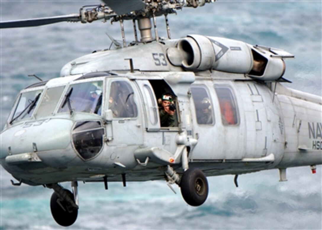 U.S. Navy Petty Officer 3rd Class Rob Gaston takes digital photographs from a MH-60S Seahawk helicopter assigned to the "Bay Raiders" of Helicopter Sea Combat Squadron 28 during a replenishment in the Atlantic Ocean, March 3, 2006.