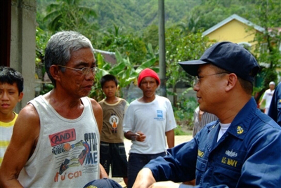 U.S. Navy Chief Petty Officer Albino Palomo speaks with one of the town elders on placement of vehicles through his tiny fishing village of Himbangen, Philippines, Feb. 21, 2006. The amphibious dock landing ship USS Harpers Ferry and the amphibious assault ship USS Essex are providing humanitarian assistance for the victims of the Feb. 17, 2006, landslide in Leyte, Philippines. 